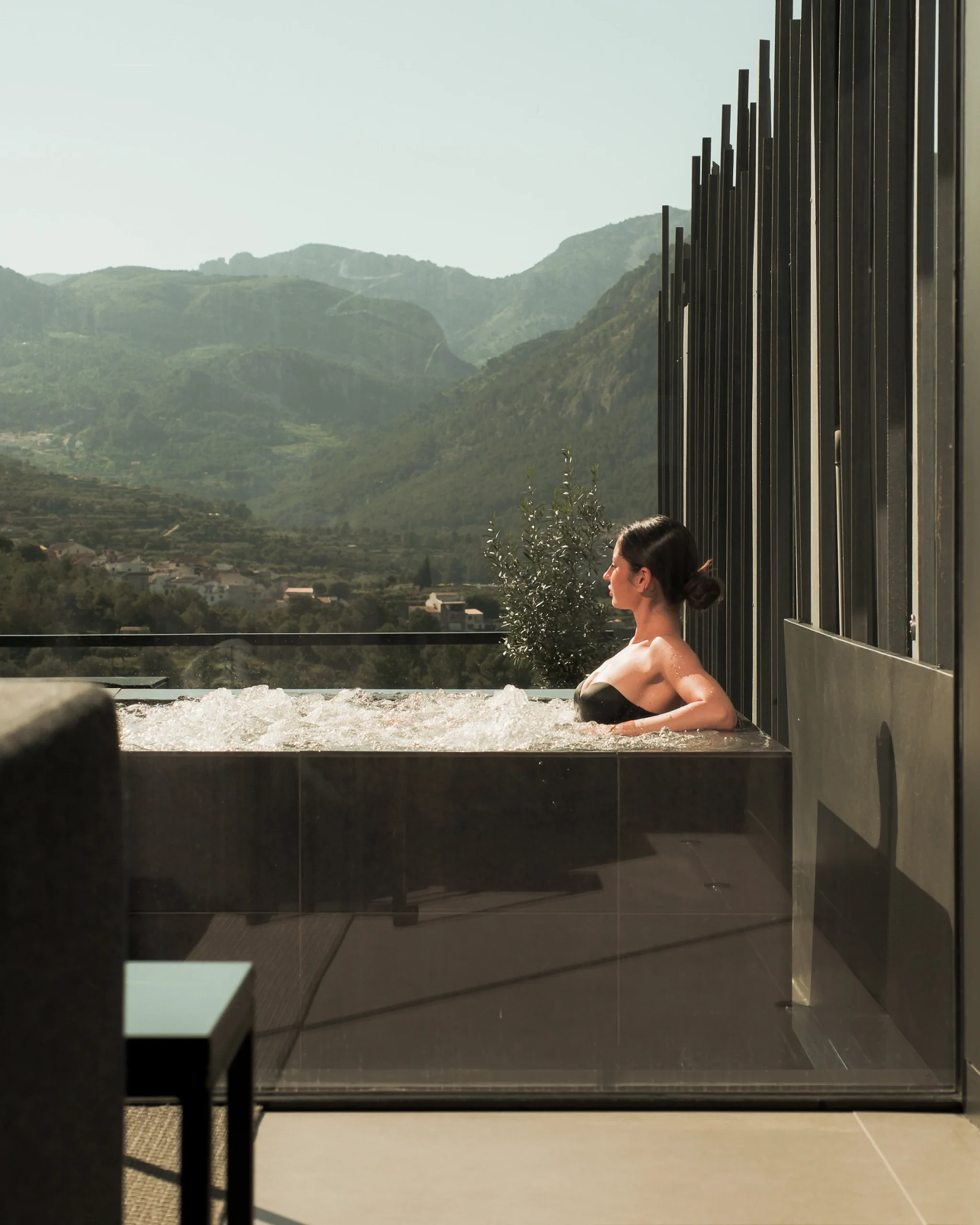 Mujer relajándose en un jacuzzi privado al aire libre con vistas a la montaña en un hotel boutique en Alicante.