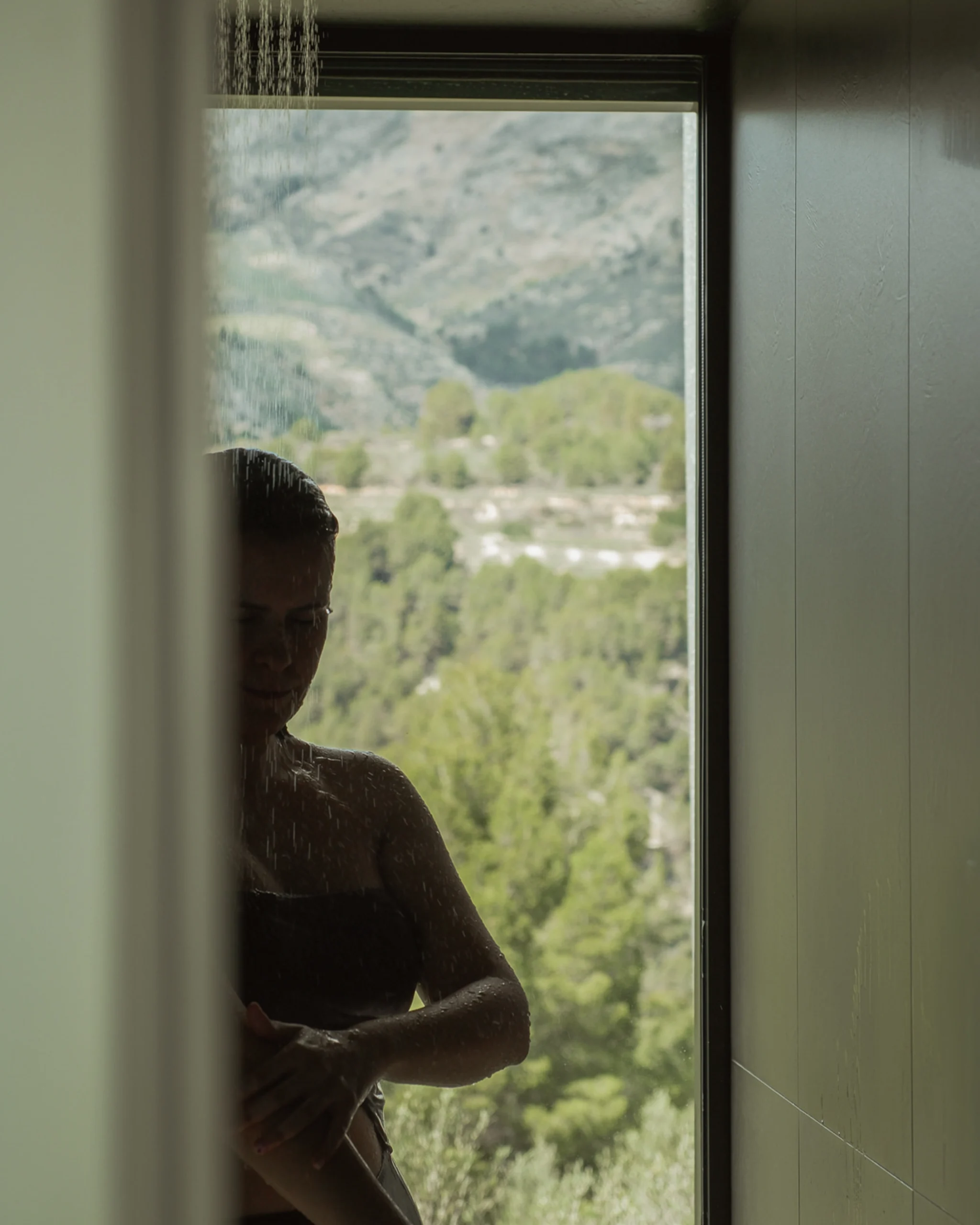 Mujer duchándose con vistas a la montaña en villa premium con diseño exclusivo en hotel solo adultos en Alicante.