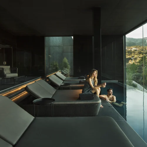 Pareja relajándose junto a la piscina climatizada interior con vistas panorámicas en un hotel spa en Alicante