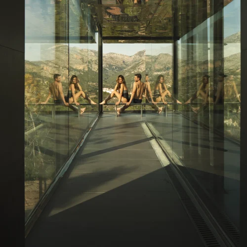 Pareja disfrutando de la tranquilidad en una zona acristalada del spa con vistas a la montaña en Alicante
