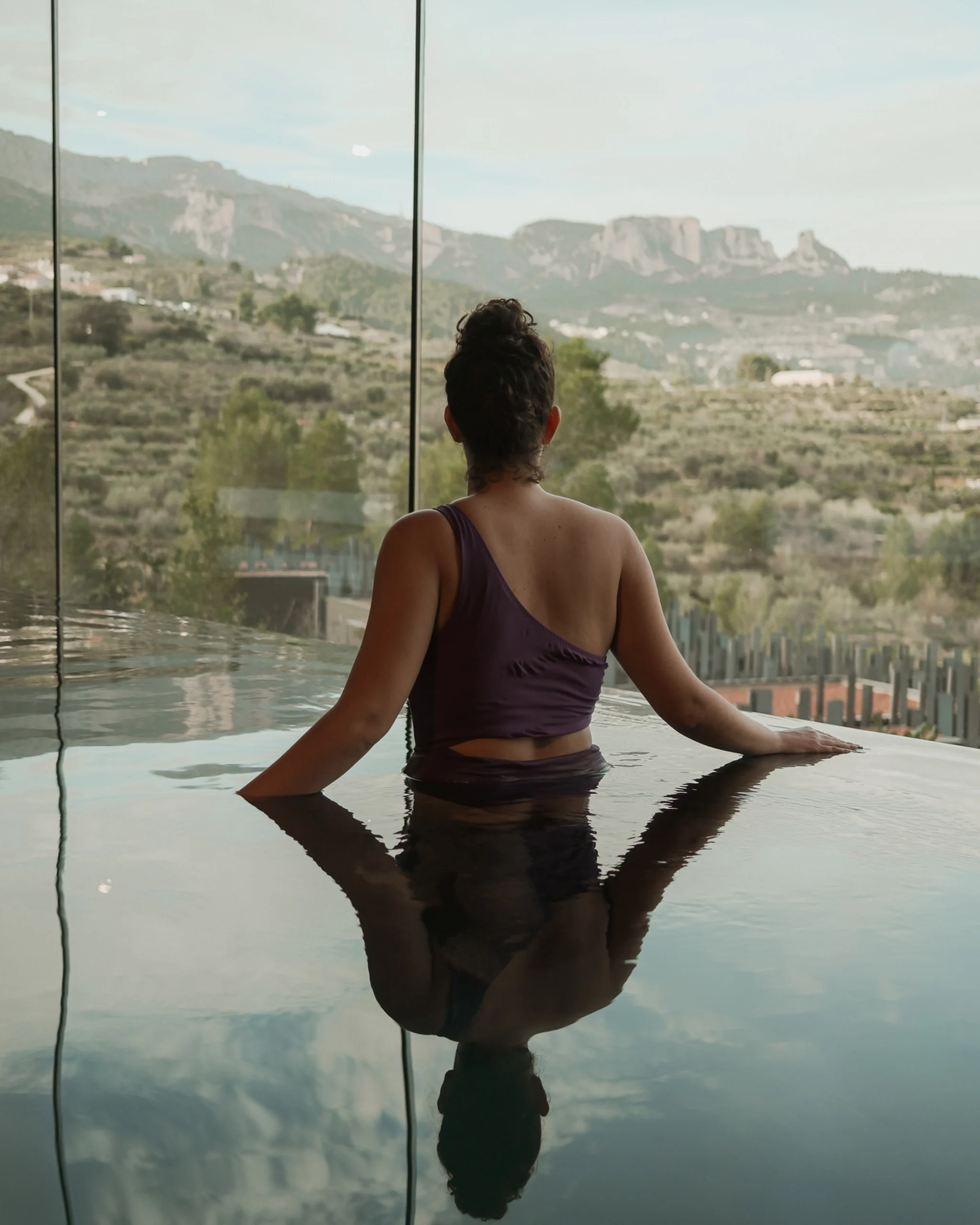 Mujer relajada en piscina climatizada interior con vistas a la montaña en Alicante