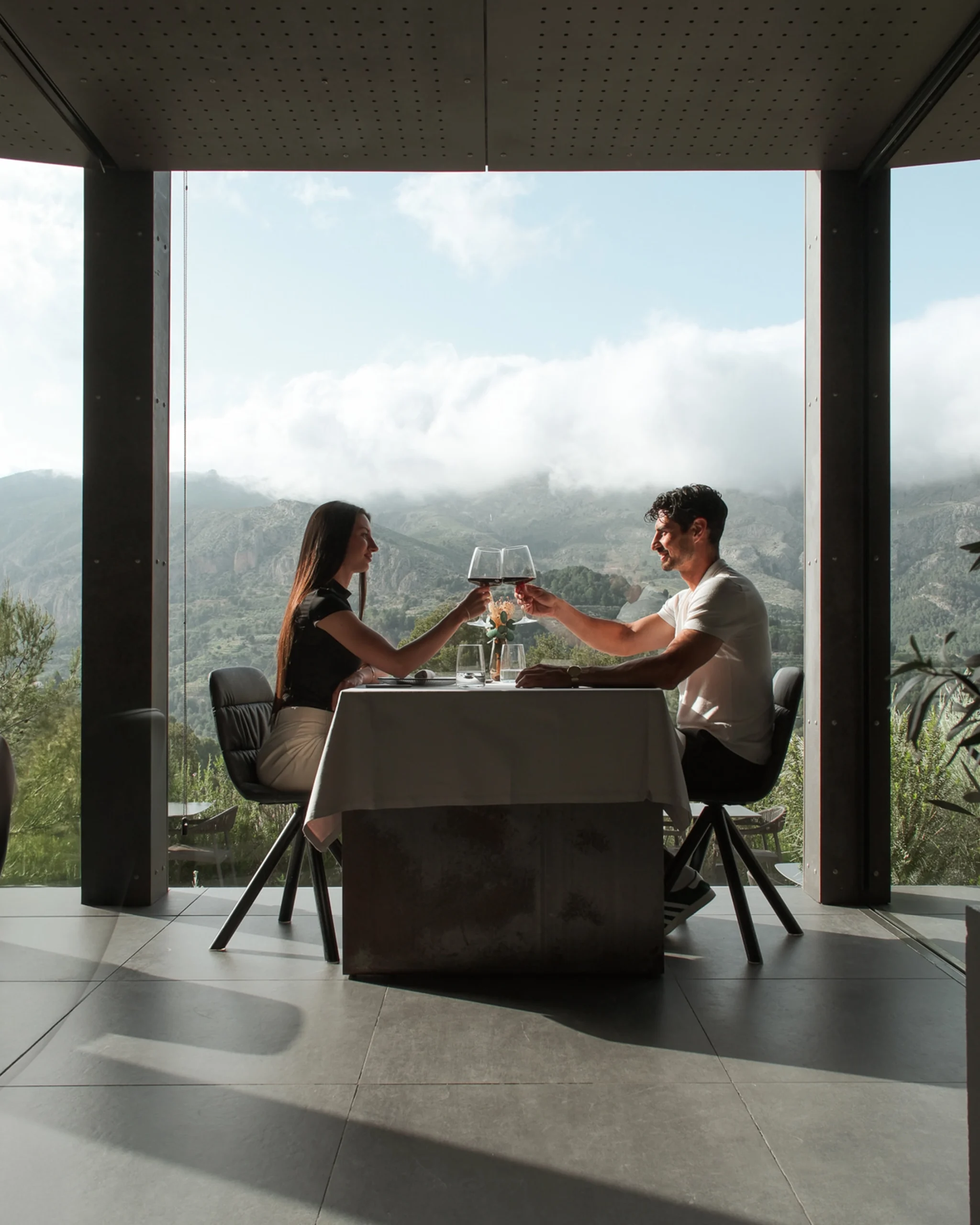 Pareja brindando con vino frente a las montañas en el restaurante panorámico de VIVOOD.