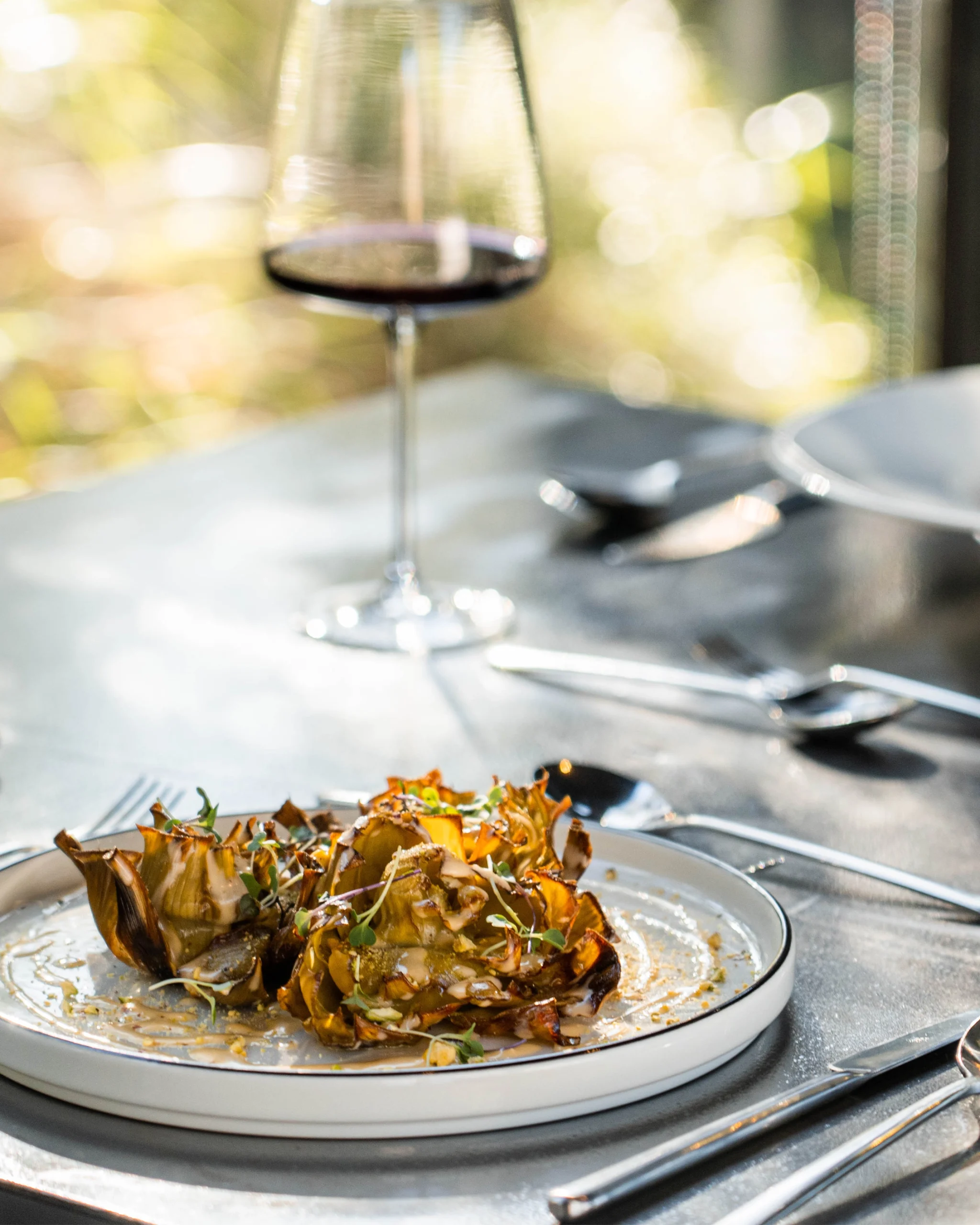 Alcachofa confitada con aliño de frutos secos y brotes, servida en restaurante gourmet con vistas a la montaña en VIVOOD.