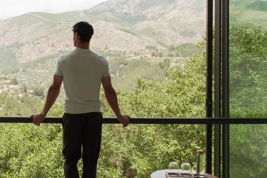 Man standing by window overlooking nature from a luxury hotel room