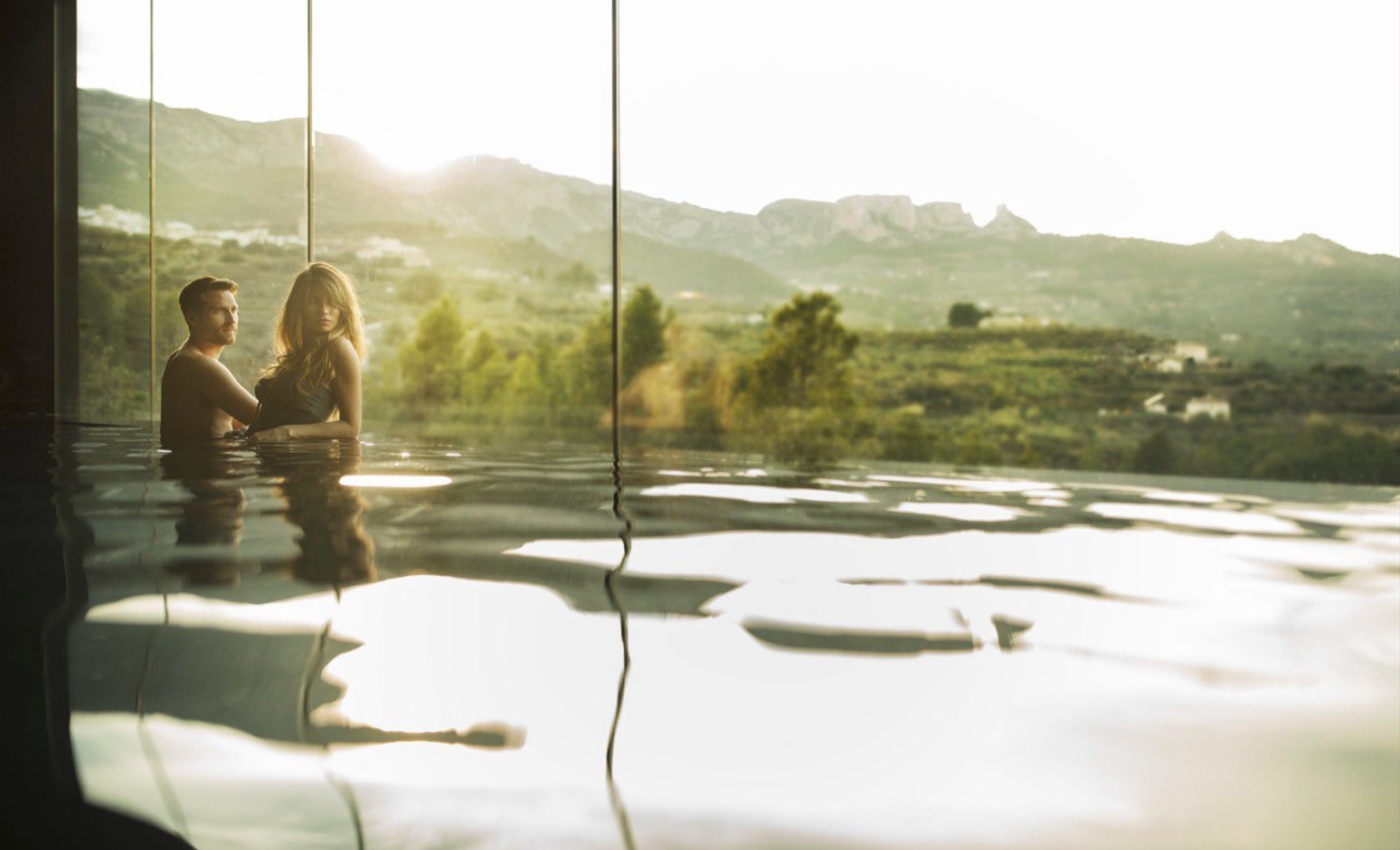 Chico y chica viendo paisaje desde piscina interior